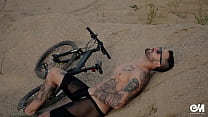自転車のストリップと彼のノーカット包皮コックを示す全身タトゥー男