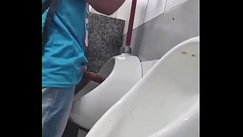 Hommes hétérosexuels en chaleur voyant des rouleaux dans l'urinoir de la salle de bain du centre commercial